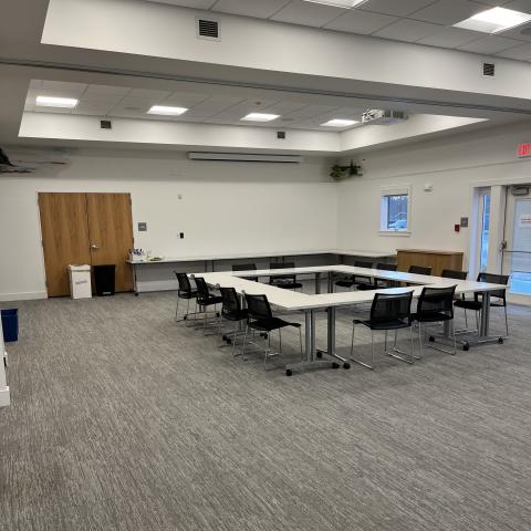 large room with tables and chairs and projector