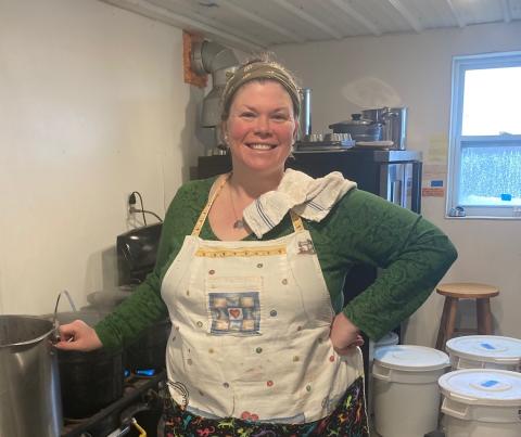 woman wearing apron standing in kitchen near pot 