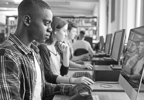 black and white photo of high school students using laptops to take the SAT