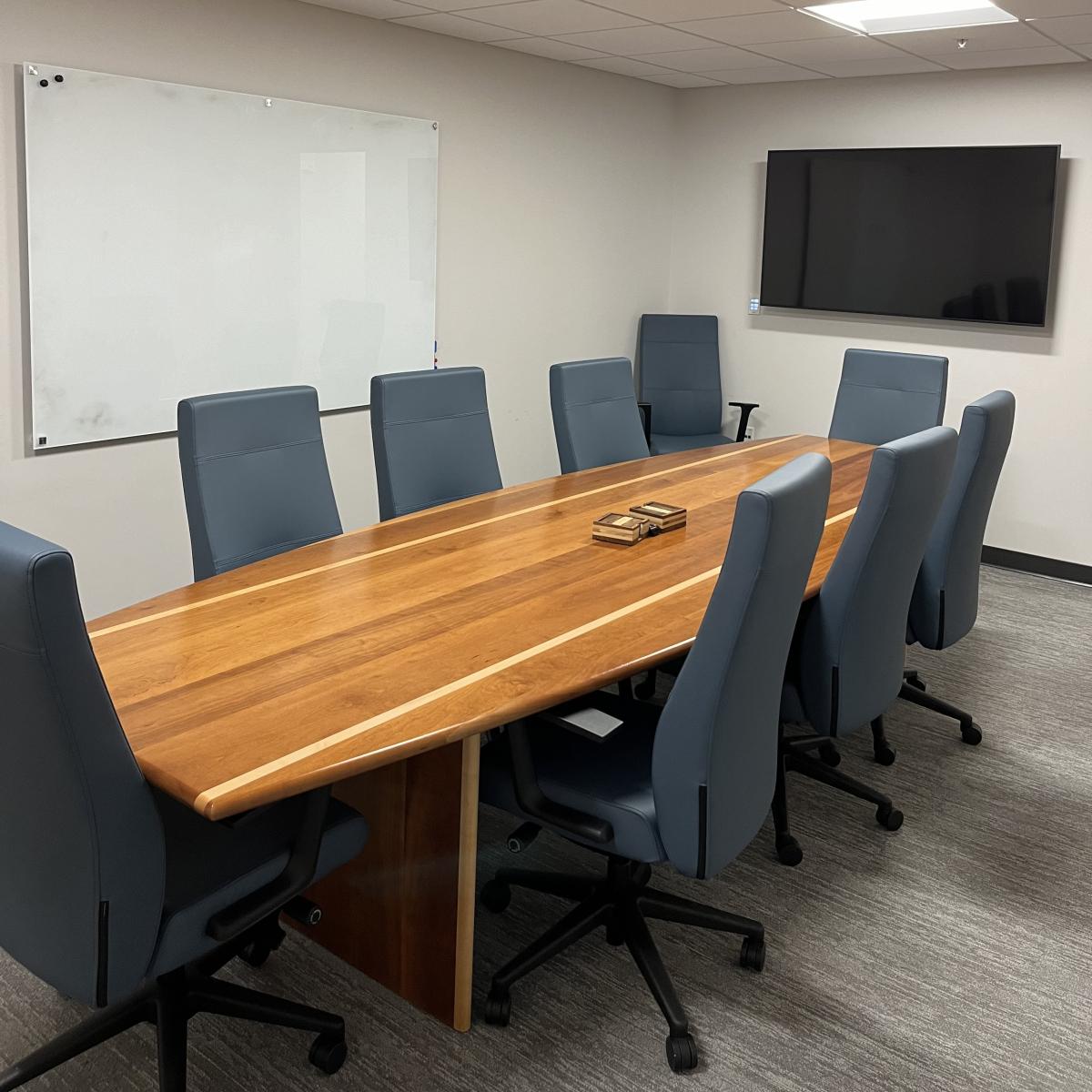 small room with table, chairs, whiteboard, and TV