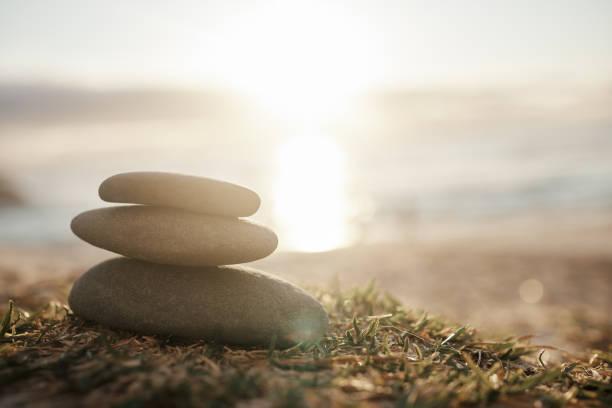 three rocks stacked with a sunny background